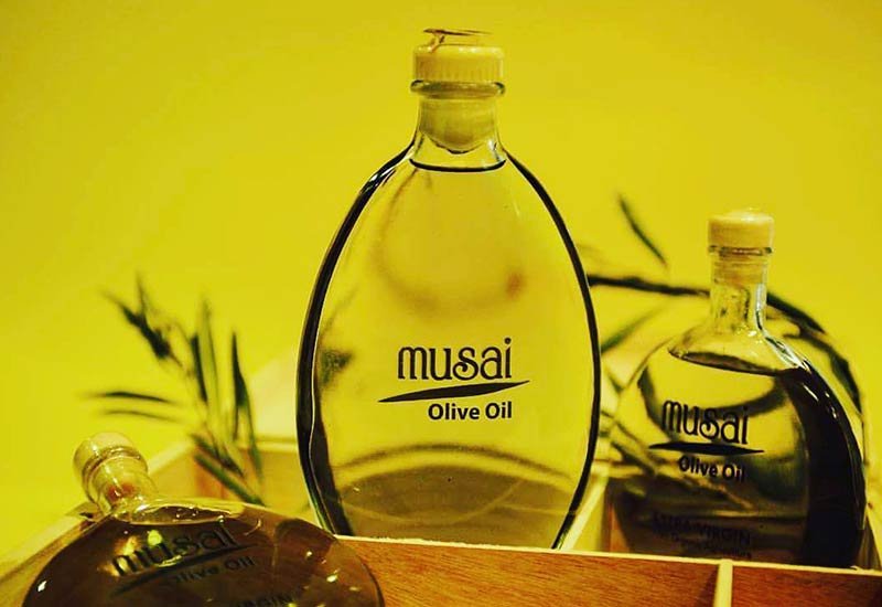 Musai extra virgin olive oil bottle with an olive branch